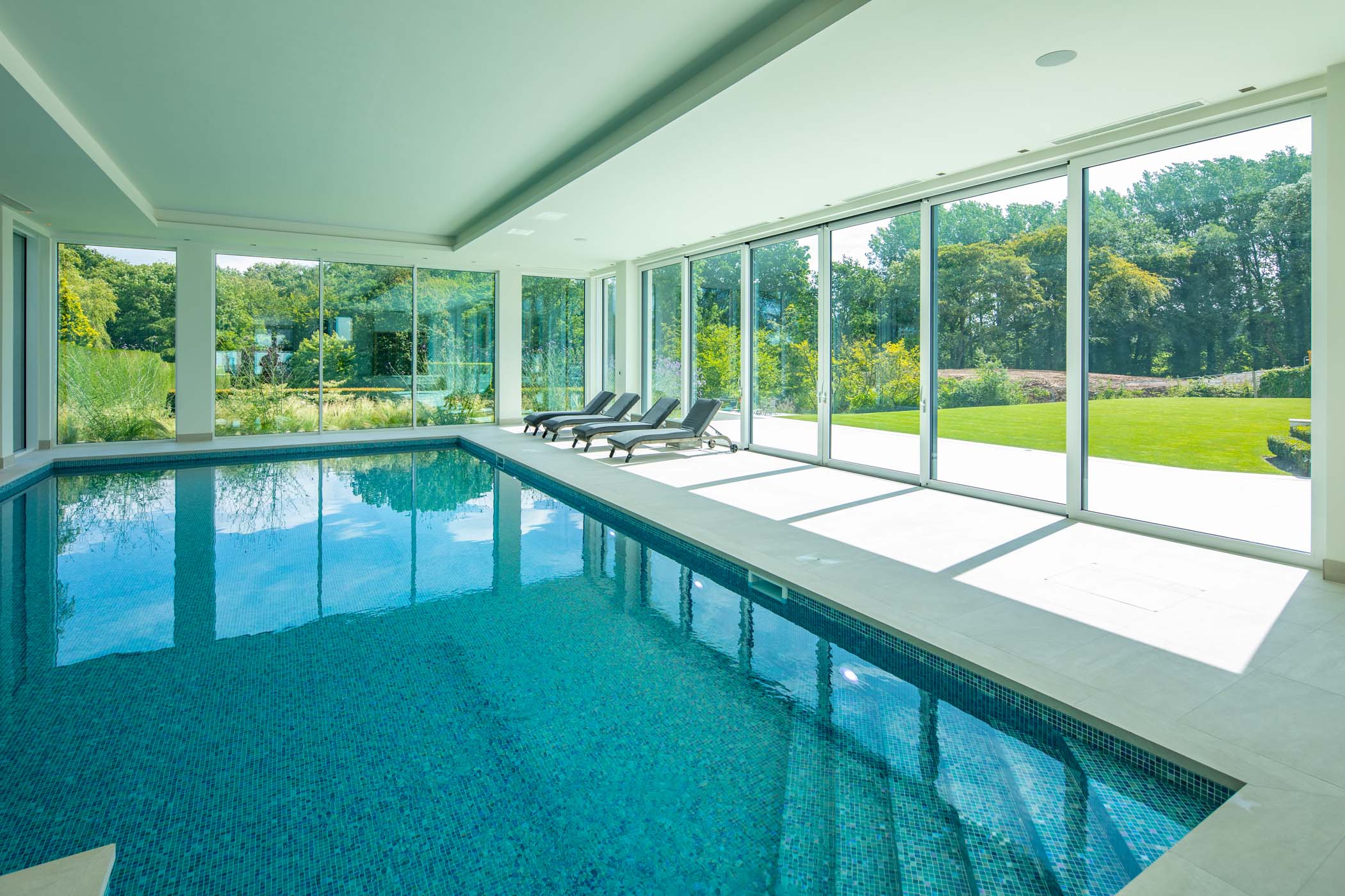 a pool house with large glass aluminium windows