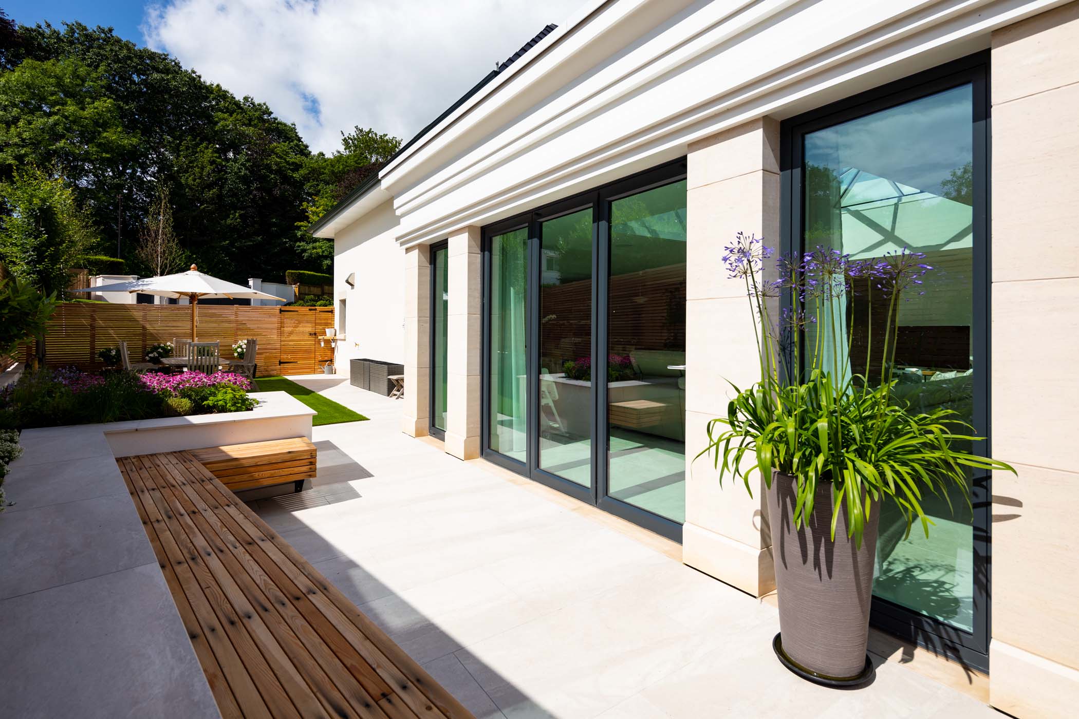 a patio with dark grey aluminium doors leading from the home